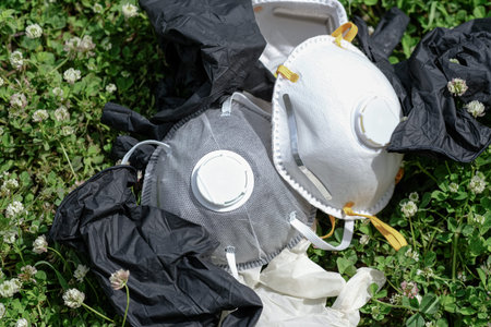 Ffp2 protective mask and gloves refuse trash on grass meadow ground.covid coronavirus disease...