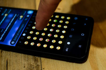 Man browsing and tap on emoji icons,smartphone messaging emoticons symbolのeditorial素材