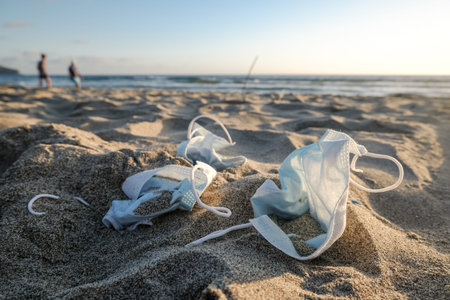 Medical face mask discarded trash on sandy beach,covid19 pandemic pollution