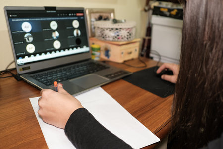 Left handed girl while doing smart school lesson video call on a laptop,covid-19 pandemic...