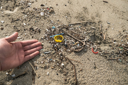 Man collect micro plastic waste on dirty ocean coast ecosystem after sea storm,nature pollutionの写真素材