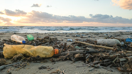 Plastic bottles discarded on pollution contaminated ocean sea coast,sunset time,environmental wasteの写真素材