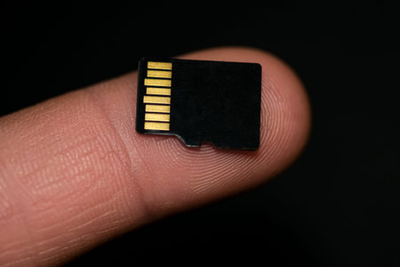 Microsd card on human finger over black background,hi tech data storage devices