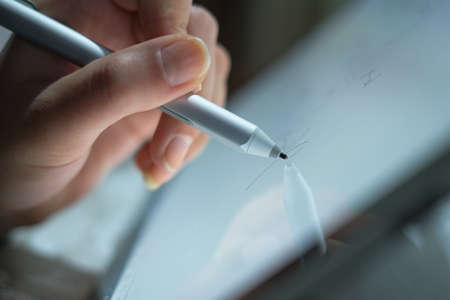 Woman hand view while using graphics tablet stylus for home smart working,digital technologyの写真素材