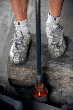 Algaida Es Pla, Majorca / Spain - August 25, 2016: A man working with the molten glass at handmade glass manufacturing factory Guardiola, Algaida Es Pla, Mallorca, Balearic Islands, Spain.のeditorial素材