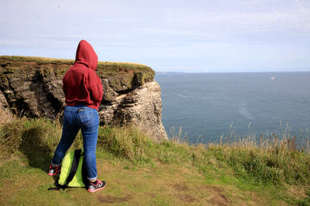 Crawton Bay (Scotland), UK - August 01, 2018: A girl looks the sea at Crawton Bay, Scotland, Highlands, United Kingdomのeditorial素材