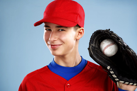 portrait of a beautiful teen baseball player in red and white uniform on colorful backgroundの写真素材