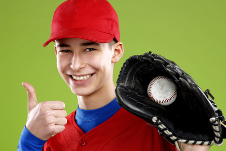 portrait of a beautiful teen baseball player in red and white uniform on colorful backgroundの写真素材