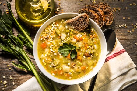 Vegetable soup with various mixed ingredients over rustic wooden backgroundの写真素材