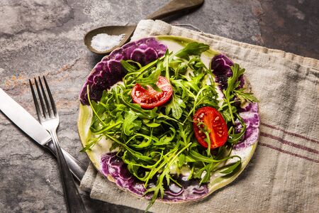 Fresh salad  tomatoes and mixed greens (arugula, mesclun, mache) on wooden background top view. Healthy foodの写真素材