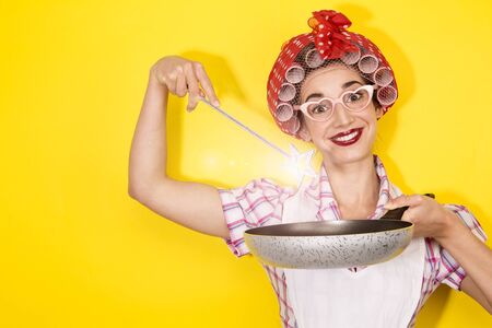 funny housewife cooking on yellow backgroundの写真素材