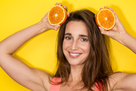 young woman with fruit on yellow backgroundの写真素材