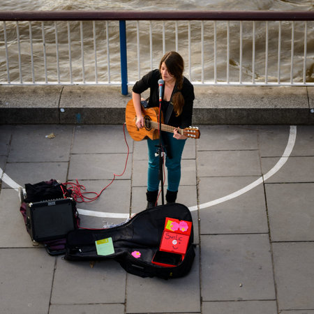 Busker street singer in London South Bank. Square format.