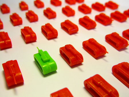 Green toy tank opposite to rows of red toy tanks to symbolize Brexit and political clash. Landscape format.の写真素材