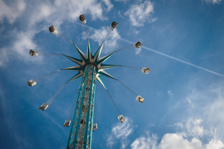 White and blue high chair swing ride in fun fair with a blue sky with clouds on the background....