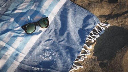 Sunglasses left on a beach towel at sunset.の写真素材