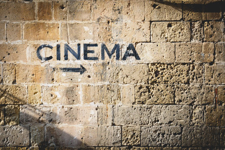 The word cinema and an arrow pointing the right side painted in black on a stone wall. Landscape format.の写真素材