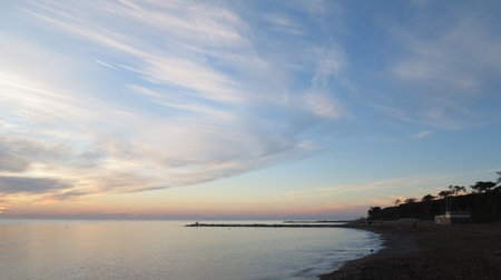 On the sandy coast of Cecina in Tuscany a moment of sky illuminated by the sun during sunsetの写真素材
