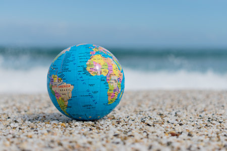 Small earth globe lies on a tropical beach. Travel and global issues concept.の写真素材
