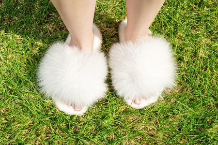 Beautiful fluffy fur slippers on women legs.の写真素材