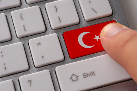 Male hand pressing keyboard button with flag of Turkey on it. Online international business concept.