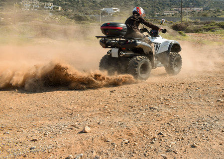A man riding ATV in sand in protective helmet.