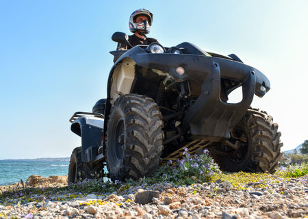 A man riding ATV in sand in protective helmet.