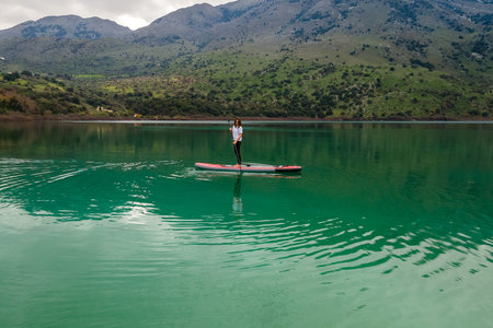 Aerial view by drone of a woman practicing Stand Up Paddle or SUP on lake.