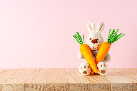 White rabbit doll with carrots on on wooden table. Minimal Easter background. Spring holidays concept.の写真素材