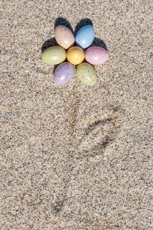 Flower shape made of colorful Easter eggs on the beach in sunny day. Easter concept.の写真素材