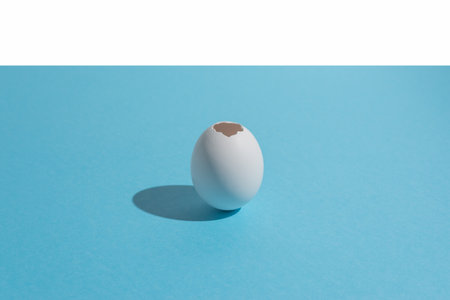 White egg shell on bright blue background. Minimal Easter concept.の写真素材