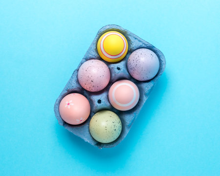 Colorful Easter eggs in carton tray on blue background. Minimal concept.の写真素材