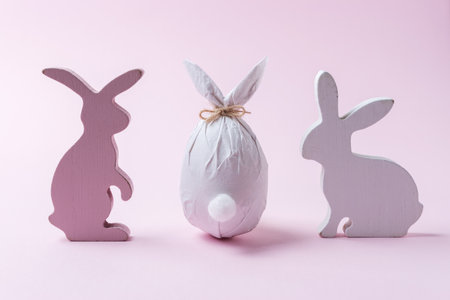 Easter egg wrapped in a paper in the shape of a bunny with bunnies decoration. Minimal Easter concept.の写真素材