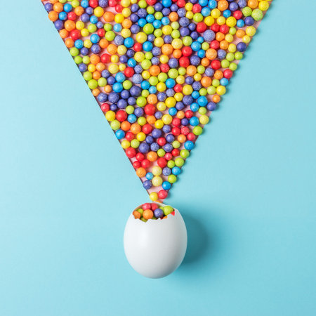 Celebration background with white egg shell and colorful party confetti. Minimal Easter concept....