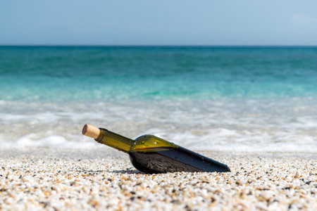 Empty bottle of wine on the beach at the summer sunny day. Sea on the background.の写真素材