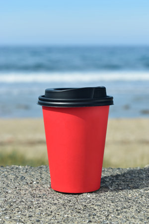 Paper cup on the background of the sea on the stones
