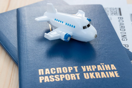 Small toy plane on top of Ukraine passports with boarding pass on a wooden background.の写真素材