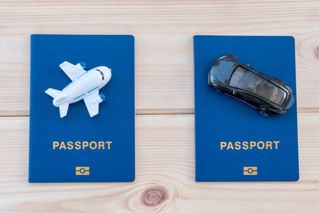 Small toy plane and toy car on top of blue passports on a wooden background.の写真素材