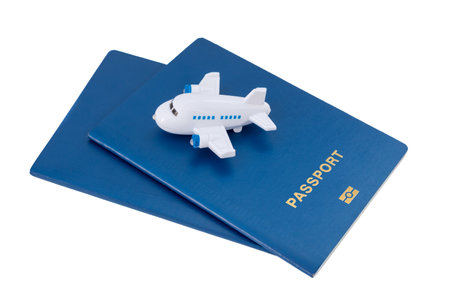 Small toy plane on top of blue passports on a white background.の写真素材