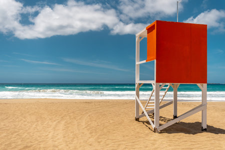 Lifeguard tower on sandy beach with sea background.