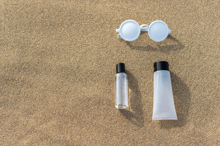 Summer beach layout with sunglasses and hand sanitizer on sand. Minimal Coronavirus outbreak. Pandemic summer concept.の写真素材