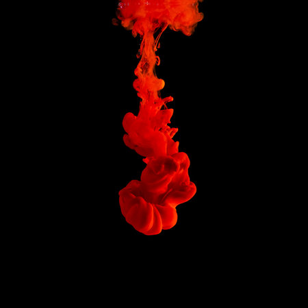 Red acrylic Ink splashes in water on black backdrop. Minimal abstract background.の写真素材