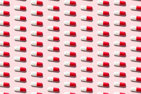 Creative pattern with red pills on pink background. Minimal medical concept.の写真素材