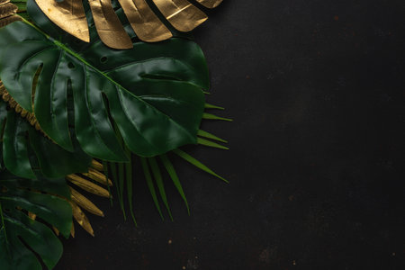Creative layout with gold and green tropical palm leaves on black background. Minimal summer abstract pattern.の写真素材