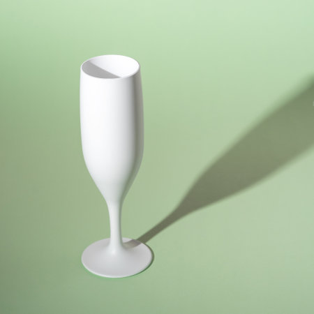 White champagne glass on green background. Minimal party concept.の写真素材