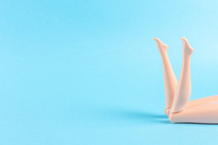 Creative composition with doll legs on blue background. Minimal summer vacation concept.の写真素材