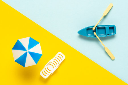 Toy beach with sun umbrella and toy boat. Vacation minimal concept. Flat lay holiday background.の写真素材