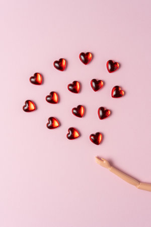 Hand of a doll with small hearts on a pink background. Love minimal concept.の写真素材