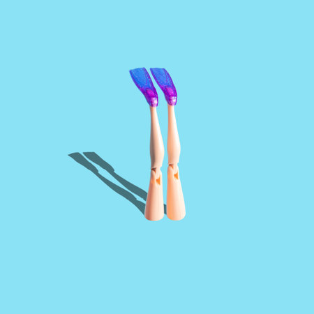 Creative composition with doll legs and flippers on blue background. Minimal summer vacation...