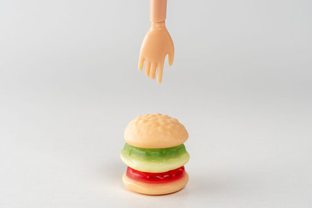 Colorful candy hamburger with a hand of doll. Minimal food concept.の写真素材
